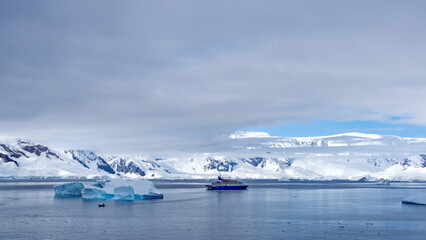 Expedition cruise ship surrounded by icebergs in a bay at Portal Point, Antarctica