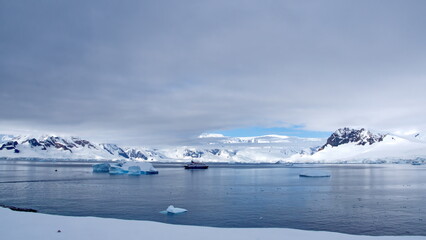 Expedition cruise ship surrounded by icebergs in a bay at Portal Point, Antarctica