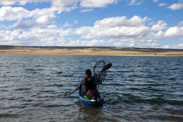 Kayaker Wearing Life Jacket Fishing on Kayak with Trolley Motor and Fishing Poles and Net in Lake Hattie near Laramie Wyoming