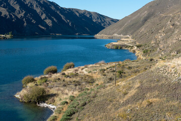 Fototapeta na wymiar Lake Dunstan bike trail as it follows the lake shore. Otago, South Island, New Zealand.