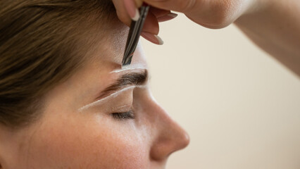 The master draws the shape of the eyebrows with white paint before coloring. 