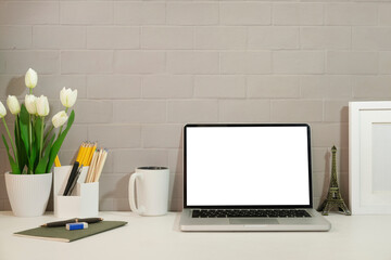 Mock up laptop computer, picture frame, coffee cup, books and pencil holder on white office desk..