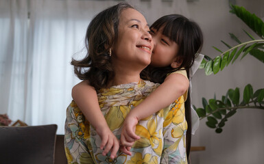 Cute little girl embracing and kissing her grandmother. Love and relation of difference generation...