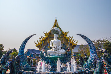Chiang Rai Province,Northern Thailand on January 19,2020:The fountain,white Buddha statue and angellic guardians in front of the main hall of Wat Rong Suea Ten or Blue Temple.(selective focus)