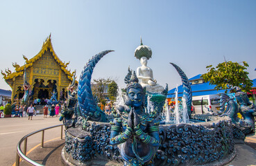 Chiang Rai Province,Northern Thailand on January 19,2020:The fountain,white Buddha statue and angellic guardians in front of the main hall of Wat Rong Suea Ten or Blue Temple.(selective focus)