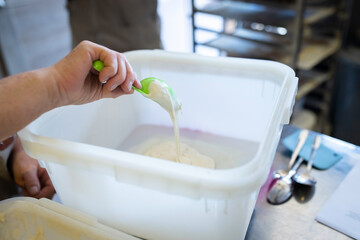 The process of making wheat bread. Sourdough is added to the mixing container. Front view.