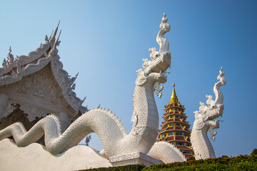 Fototapeta Wat Huay Pla Kang,Rimkok district,Chiang Rai Province,Northern Thailand on January 19,2020:Beautiful white Naga staircases of the prayer hall,with 9 layers pagoda in the distance.(selective focus) obraz