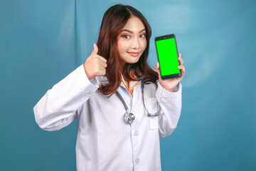 Young Asian woman doctor is pointing and showing green screen or copy space on her smartphone. showing thumbs up or OK sign. - Powered by Adobe