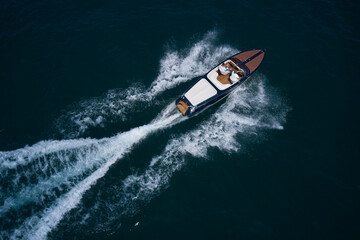 Luxurious wooden boat fast movement on dark water..Classic Italian wooden boat fast moving aerial view. Top view of a wooden powerful motor boat. - obrazy, fototapety, plakaty