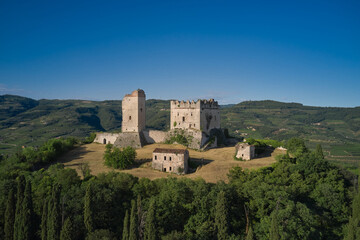 Obraz premium An ancient castle in Italy surrounded by vineyards is a point of interest. Scaliger Castle of d'Illasi in the province of Verona, built in the 10th century. Medieval castle on a hill aerial view.