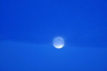 Bright full moon in early evening sky