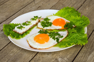 Healthy breakfast - fried eggs, bread with cheese and fresh parsley on a white plate