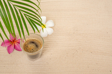 Fototapeta na wymiar Glass Espresso On Sand Beach Next To Palm Leaf.
