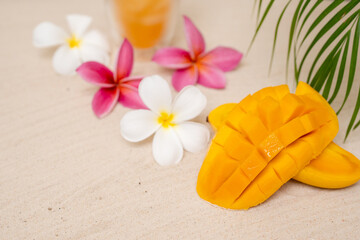 Beautiful Slice Mango On sand Beach Next To Palm Leaf And Frangipani Flowers.