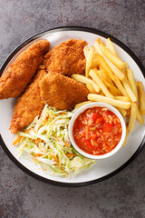 Barberton fried Chicken with French fries, cabbage salad and hot sauce close up in the plate on the table. Vertical top view from above
