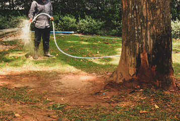 Workers water the grass in the park.