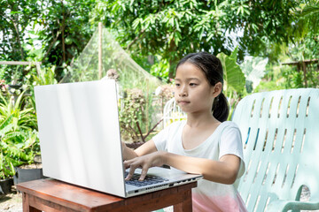 Little asian girl using white laptop to learning at home.Out door home school.