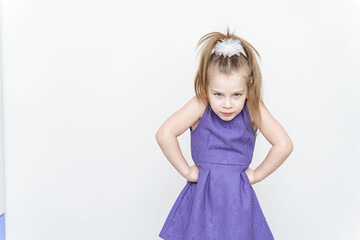 portrait of an angry little girl in a purple dress with a posing on a light gray background