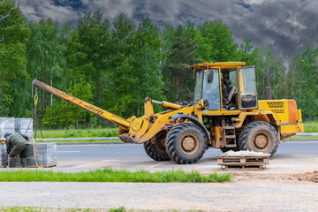 Powerful wheel loader for transporting bulky goods at the construction site of a modern residential area. Construction equipment for lifting and moving loads.