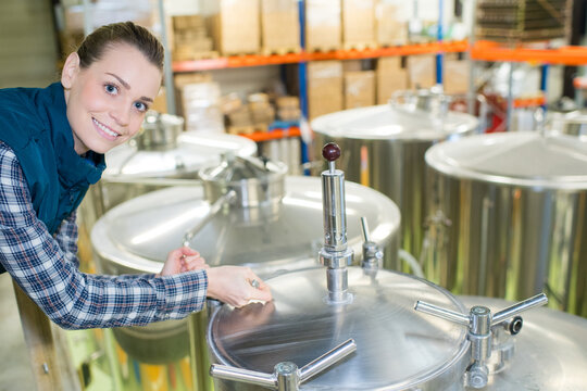 portrait of woman in brewery stood next to vats