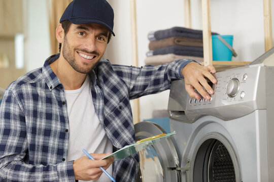 Repairman Repairing Washing Machine In The Kitchen