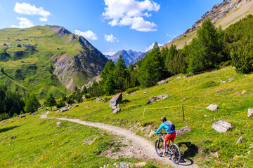Fototapeta na wymiar Woman tourist cycling on mtb bike in beautiful Alpisella valley on sunny summer day, Alps Mountains, Italy