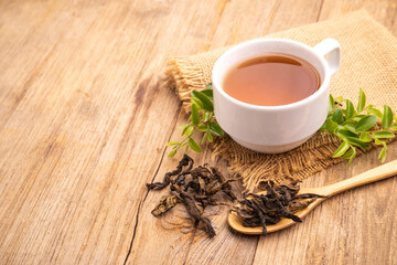 Obraz na płótnie Canvas White cup of hot tea and dry tea leaf on wooden table