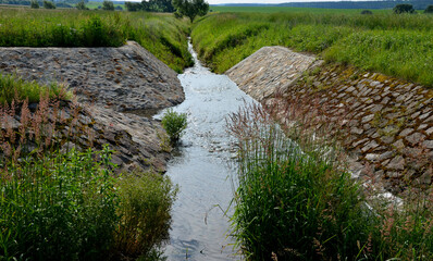 stone lining of bank at the mouth of the sewer pipe with a grate against the entry of persons into...
