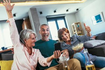 Group of senior friends support favorite sports team together use smartphone app to online bet