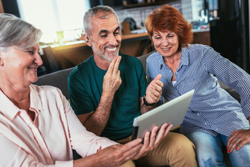 Smiling Deaf man with his friends talking using sign language on the tablets's cam