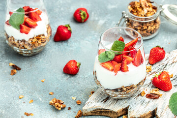 Parfait with fresh fruit, greek yogurt, oat granola, honey and mint leaves in glass jar on a wooden board. gluten free diet, Healthy breakfast. place for text, top view