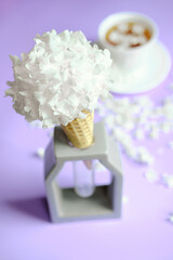 Waffle cone with hydrangea on purple background. Delicate still life with flowers. flower ice cream. Veri Peri trendy color.
