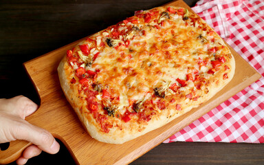 Hand Placing Fresh Baked Pizza Alla Pala (Roman Style Pizza on a Paddle) on the Table