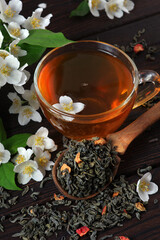 green tea with jasmine on the table. green tea leaves, jasmine flowers and cup of tea close-up. top...