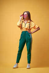 Colorful full length studio portrait of young girl with long hair. Yellow background.