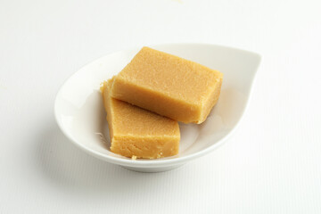 An Indian sweet originated from Mysore made from Ghee called  served on a white plate on a white background