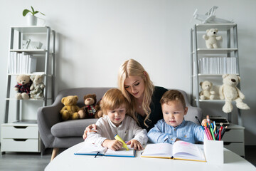 Teacher mom working with creative kids. Teacher helps school kids to learn lesson.