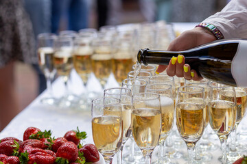 A banquet table with wine glasses and plates with strawberries.
