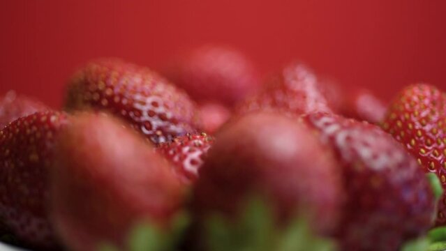 Fresh heap of ripe wild strawberries rotates. Summer strawberry harvest on a plate close-up.