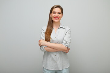 Smiling woman standing with arms crossed, isolated female studio portrait, young lady dressed pants and gray shirt