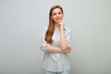 Smiling thinking woman with her chin on hand, isolated female portrait, young lady dressed pants and gray shirt.