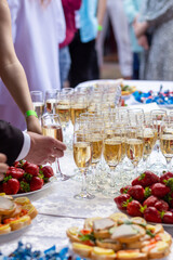 A banquet table with wine glasses and plates with snacks.