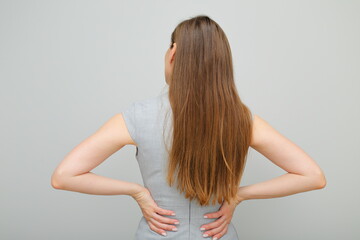 Obraz premium Woman in business dress standing back and keeps hands on hips, female portrait with long hair. Back view. Rear view.