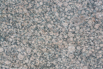 Granite texture. Natural gray granite with a grainy pattern. Stone background. Solid rough surface of rock. Durable construction and decoration material. Close-up.