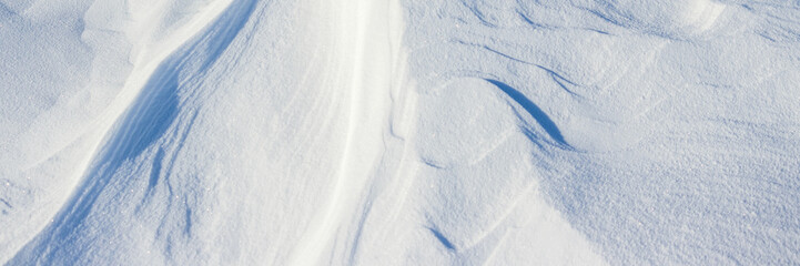 Snow texture. Wind sculpted patterns on snow surface. Wind in the tundra and in the mountains on the surface of the snow sculpts patterns and ridges. Arctic, Polar region. Winter panoramic background.