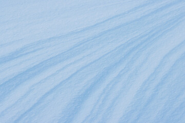 Beautiful winter background with snowy ground. Natural snow texture. Wind sculpted patterns on snow surface.