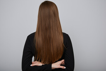 Naklejka premium Back woman with long hair and crossed arms. Girl in black shirt isolated portrait.