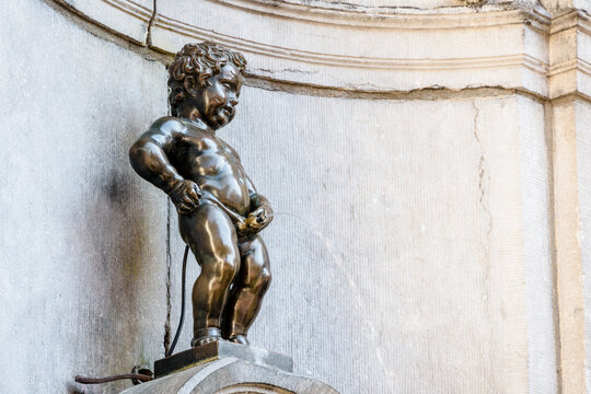 Brussels, Belgium - April 21, 2019: Manneken Pis is a historic fountain in the old town, made of a bronze statue by Jerome Duquesnoy the Elder, depicting a naked little boy standing and urinating.