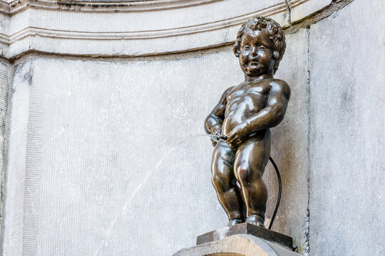 Brussels, Belgium - April 21, 2019: Manneken Pis is a historic fountain in the old town, made of a bronze statue by Jerome Duquesnoy the Elder, depicting a naked little boy standing and urinating.