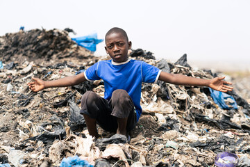 Young black African boy inviting the viewer to contemplate the chaos of garbage, decay and filth...